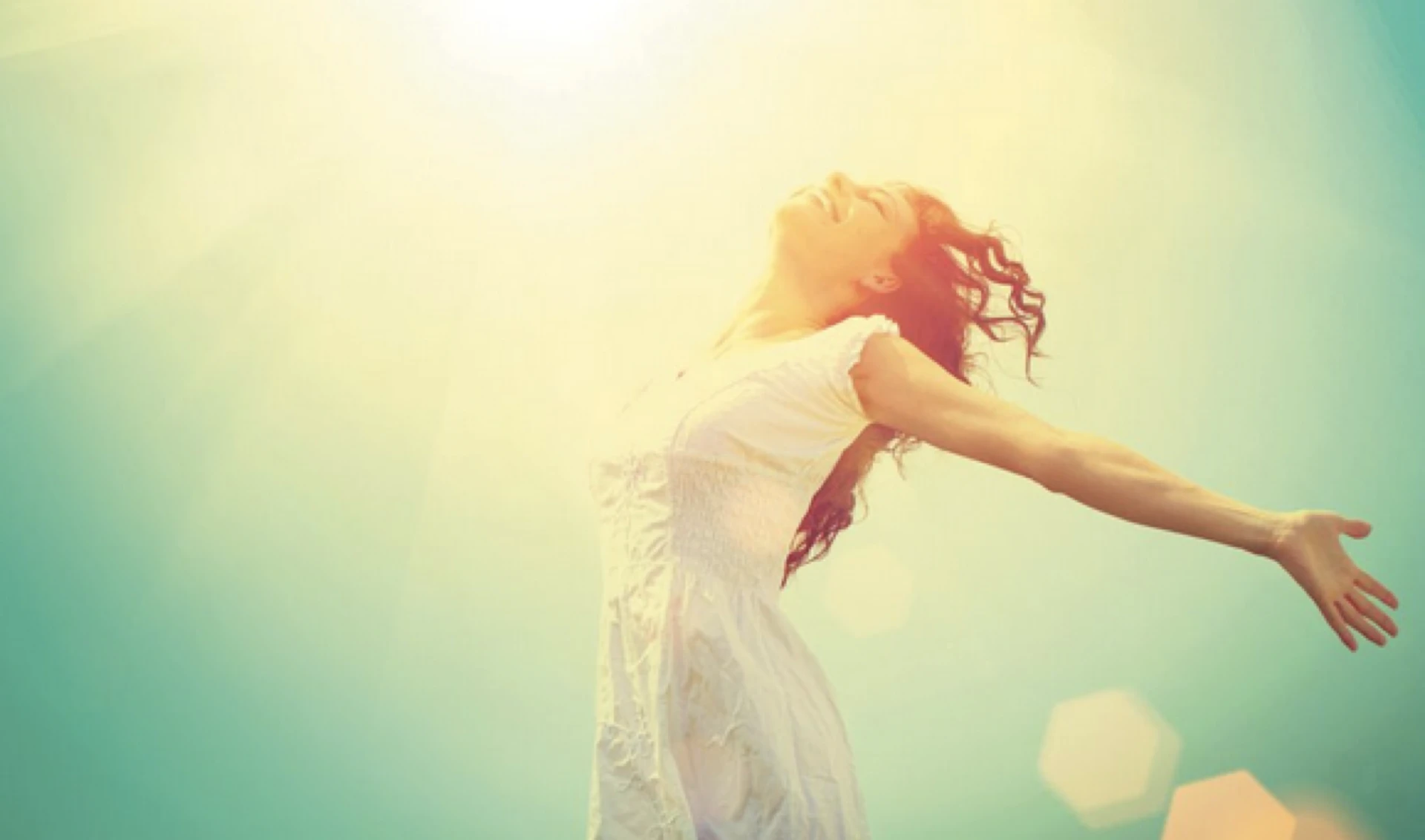 A woman with arms open wide in golden sunlight