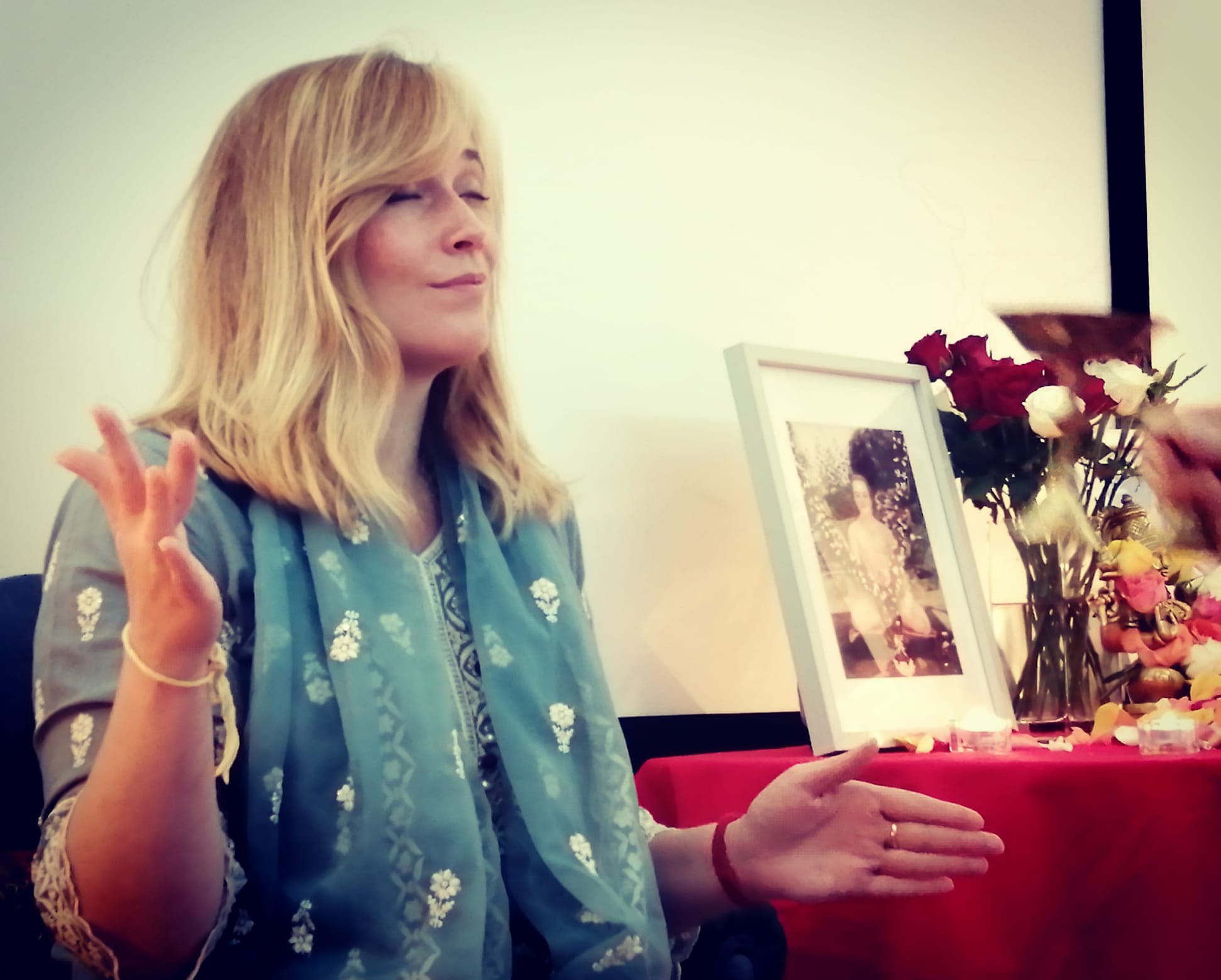 Gayatri leading a ceremony beside a flower-filled altar