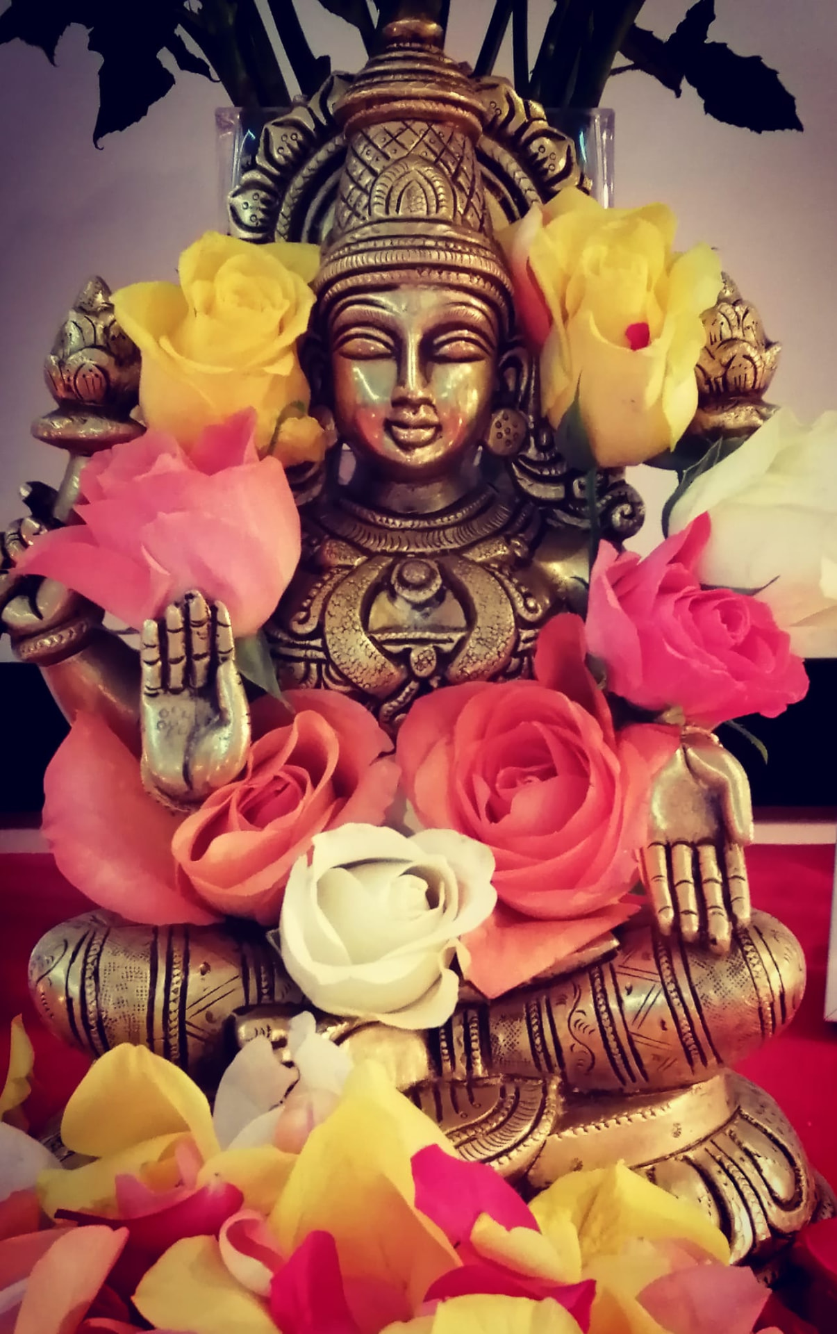 Brass statue of the goddess Lakshmi adorned with roses and petals